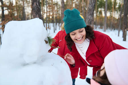 Cheerful loving family playing outside in snow. Happy smiling caring and loving mom creating a...
