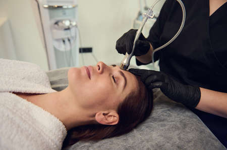 Close-up woman receiving a facial treatment on her face. Microdermabrasion therapy, anti wrinkles,...