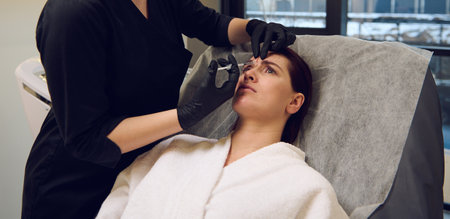 Cosmetologist beautician aesthetician holding a syringe and making a beauty injection of botulinum toxin in the forehead of middle aged woman in wellness spa clinic for rejuvenating anti-aging therapyの写真素材