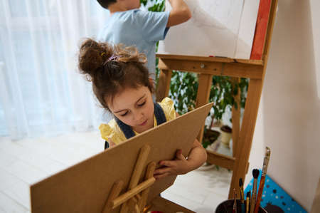 Art class. Adorable Caucasian kids paint on canvas with watercolor and oil paints. The concept of hobbies, art, creativity and children's entertainmentの写真素材
