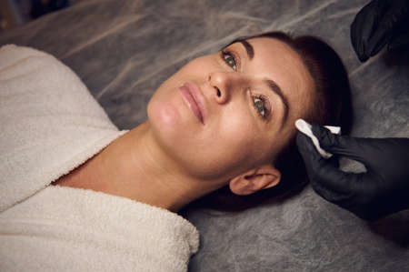 Attractive middle aged Caucasian woman receiving a professional face skin care in wellness spa...