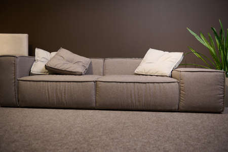 Front view of a large comfortable sofa made of high quality fabrics and soft cushions, on display for sale in the showroom of a furniture store. Home interior design, living room decorationの写真素材