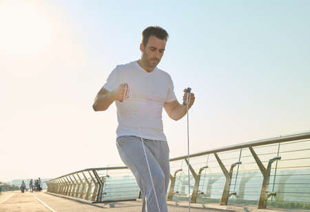 Handsome middle aged sportsman, muscular build Caucasian middle aged man training with jumping rope...