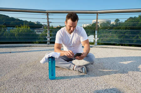 Middle aged European man, athlete using fitness tracking app on smartphone. Determined sportsman...