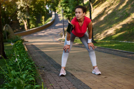 Female runner, athlete, sportswoman resting in the city park while feeling exhausted during jogging...