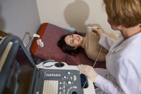 Doctor radiologist giving beautiful young female patient an ultrasound diagnostics for timely...