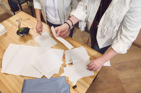 Overhead view of a skilled team of fashion designers working at a wooden table in clothing design...
