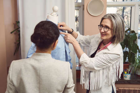 A skilled team of fashion designers tailors try on the new collection of women's dress shirt on a...