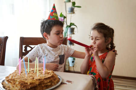 Charming adorable Caucasian kids, boy and girl, brother and sister celebrating birthday party at...