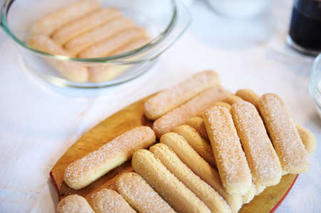 Flat lay composition of Tiramisu ingredients: savoiardi biscuit cookies on a wooden board. Copy...
