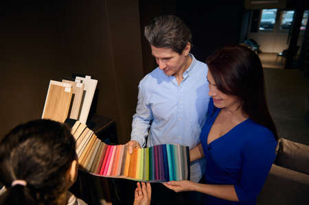 Overhead view of a middle-aged Caucasian couple choosing upholstery for a sofa, looking at samples...