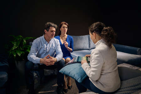 Rear view of an interior designer showing a palette of fabric samples for upholstery to a couple...