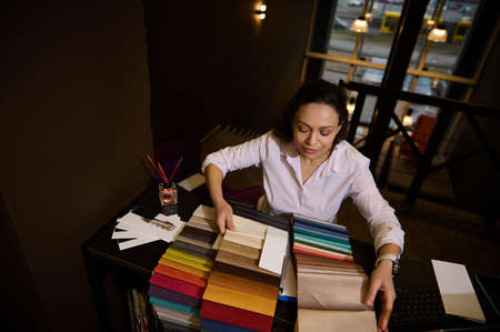 Inspired creative woman- interior designer in an upholstered furniture store works with various...