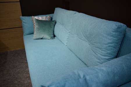 Cropped view of a beautiful comfortable minimalist stylish art nouveau turquoise sofa with patterned...