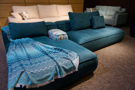 Stylish modern, art nouveau, comfortable sofas with cushions and blankets in living room interior. Upholstered furniture store, home design conceptの写真素材