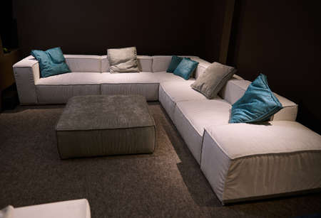 Comfortable upholstered beige couch with colored stylish green cushions displayed for sale in the furniture store showroom.の写真素材