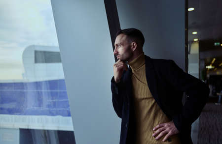Charming thoughtful Middle Eastern man transit passenger looking through panoramic windows...