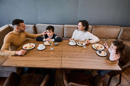 Happy Caucasian family enjoying lunch together in a restaurant in the airport departure terminal, waiting to board the flight. Food and drink, travel conceptの写真素材
