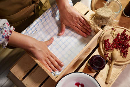 Housewifes hands arranging jars with handmade jam upside down in a wooden crate and covering them with a waffle towelの写真素材