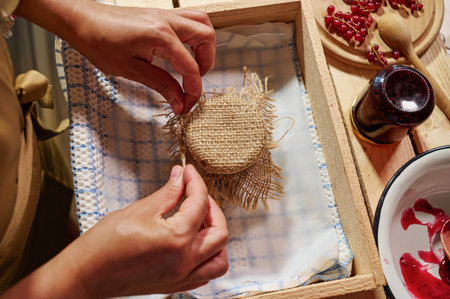 Housewife tying bow on burlap, decorating the cover of a jar with homemade jamの写真素材