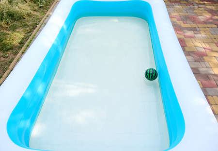 Inflatable swimming pool with a small floating toy ball in the backyard of a private residence