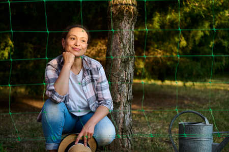 Charming dreamy beautiful Caucasian woman gardener agronomist, cutely smiling while planting...