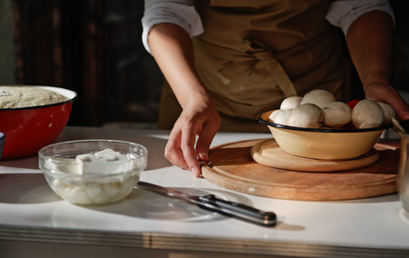 Close-up of food ingredients on a white table against a woman housewife in a chefs apron on rustic...