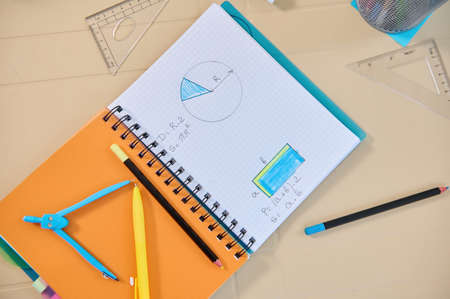 Copybook with geometry examples for solving in primary school. Drawing compass and school supplies...