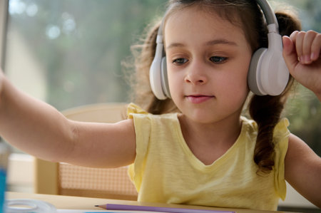 Close-up portrait of European child girl of preschool, listening to the music in wireless...