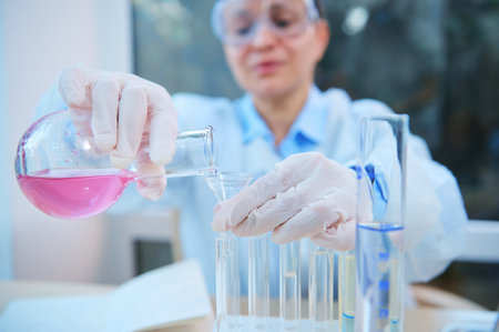 Close-up. Hands of a scientific researcher pouring liquid through a funnel from a glass laboratory...