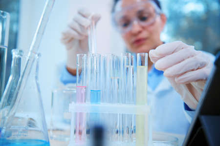 Selective focus on test tubes with chemical fluid substances, next to laboratory glassware over...