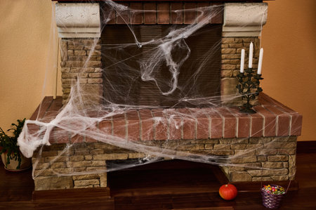 A cobweb-covered stone fireplace with candles on a rusty candlestick. Halloween house decoration. October 31. Home decor. Interior Design. Gothic holidayの写真素材
