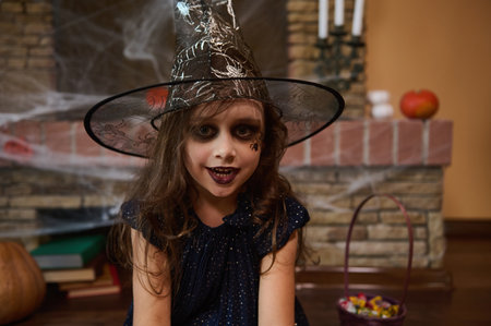 Close-up portrait of a gothic little child girl, with a spider painted on her cheek, wearing a...