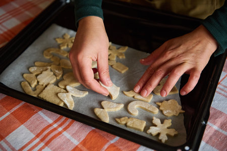 Selective focus on chef confectioners hands, over a baking sheet with carved molds of gingerbread...