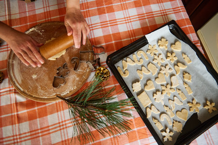 Top view. Selective focus. Housewifes hands roll out dough with a rolling pin, a baking sheet with...