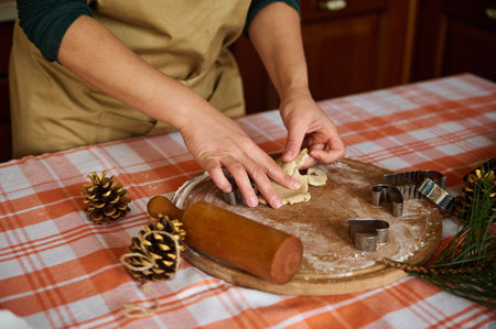 Close-up of a woman housewife, wearing a beige chefs apron, preparing homemade gingerbread cookies...