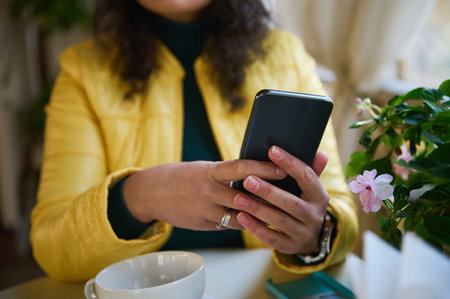 Selective focus on hands of a woman holding a smartphone, chatting, browsing websites, checking...