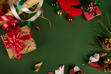 Christmas background with copy advertising space. Beautiful gifts with wrapping materials, decorative tapes, rope and tied bows on a green surface. Boxing Day. Packing presents. Mockup. Festive moodの写真素材