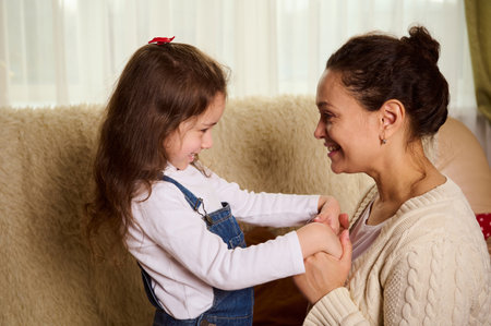 Happy middle-aged pretty woman, a loving mother and her little child daughter smiling, hugging,...