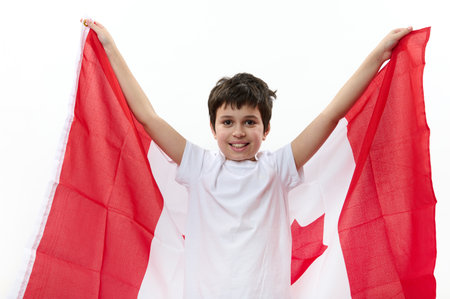Happy Canadian citizen, a teenage boy wearing casual t-shirt and blue denim jeans, carrying a flag of Canada, celebrating the independence Day on July 1. Concept of freedom, liberty and citizenshipsの写真素材