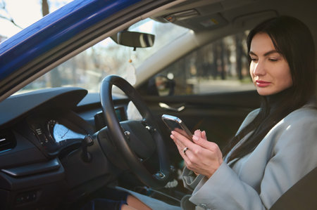 Confident successful middle-aged businesswoman, dressed in winter coat, sitting in the car on...