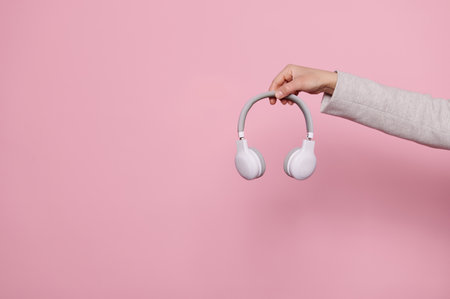 Hands holding wireless headphones over pin isolated background with copy advertising space. Music industry. People. Entertainmentの写真素材
