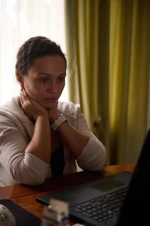 Freelancer woman sitting at laptop, feeling stressed out and dizzy from her job, telecommuting from...