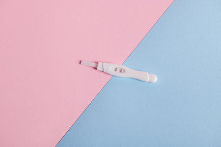 Isolated flat shot of positive pregnancy test kit on pink and blue pastel bicolor background. Motherhood concept. Womens health and fertility concept. Health care and medicine. Copy advertising spaceの写真素材