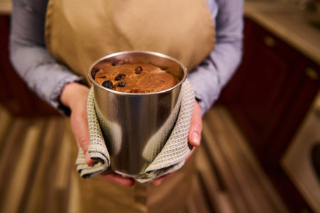 Selective focus on a tin baking dish with freshly baked Easter cake panettone in the hands of a...