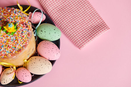 Cropped view of Easter orthodox sweet bread and colorful eggs on light pink pastel background....