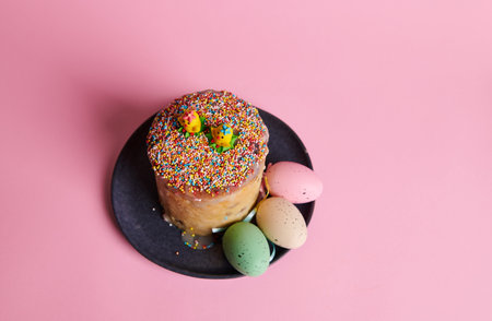 View from above od a sweet Easter bread and eggs on navy ceramic plate on isolated pink pastel background. Celebrating Christian religious holiday - symbol of the resurrection of Jesus Christの写真素材