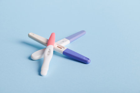 Pregnancy tests on blue background. Womens health, fertility, planning maternity and pregnancy concept. Stack of test kits with positive results. Copy advertising spaceの写真素材