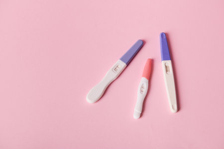 Top view of inkjet pregnancy test kits with a biochemical reaction between hCG and urine appearing in two bars, isolated pink color background. Ovulation day. Planning maternity. Gynecological conceptの写真素材