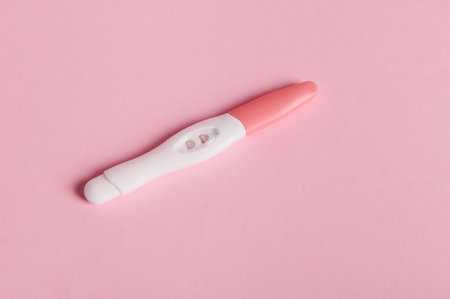 Positive inkjet pregnancy test kit on pink color background. Rapid diagnosis of pregnancy at home. Copy advertising space. Womens health. Ovulation date calculation. Planning pregnancy and maternityの写真素材